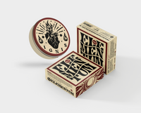 By Elementum Ignis Oil-Based Pomade - pot met hart-logo tegen twee verpakkingsdozen