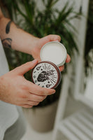 By Elementum Ignis Oil-Based Pomade - open pot in handen met cremekleurige inhoud en Ignis-deksel